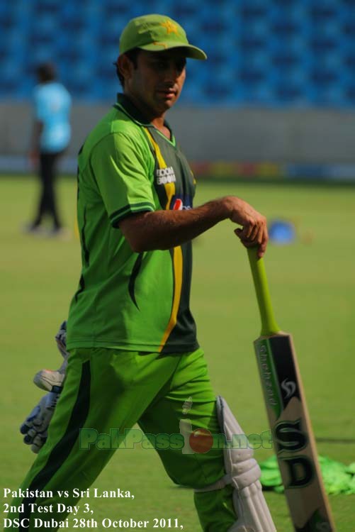 Saeed Ajmal dangles the bat as he walks along