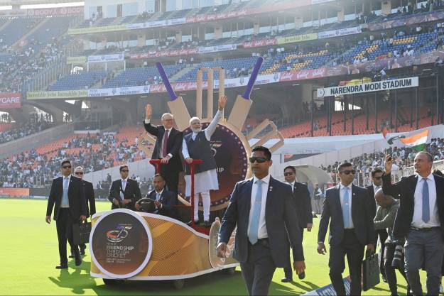 The prime ministers of India and Australia are driven out on to the stadium field  