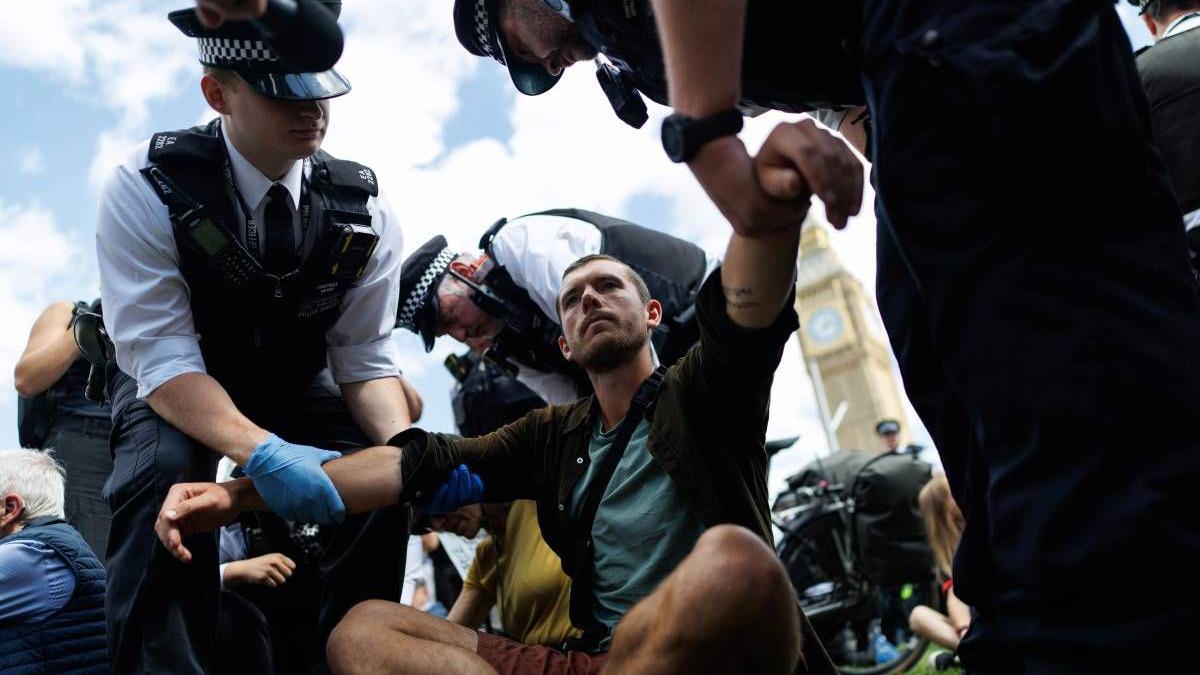 Police officers arrest a man during a mass protest in Parliament Square Police officers arrest a man during a mass protest in Parliament Square